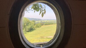 A window with a view of a green field and trees. - Pet Friendly - 2 Guests - Shepherds Hut (Longhope)