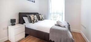A bedroom with a bed, bedside table, and a window. - Impeccable 2-Bed Apartment in Reading (Reading)