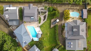Vista aerea di una zona residenziale con diverse case, una piscina e un piccolo stagno.
