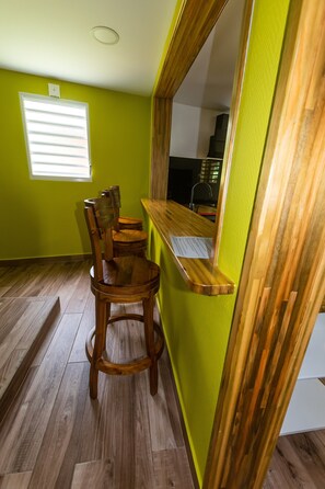 Ein Zimmer mit Holzboden, grüner Wand und einem Fenster mit Jalousien.