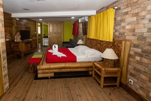 Ein Zimmer mit einem Bett, einem Holztisch, einem Fernseher und einem durchgegangenen Tür sichtbaren Badezimmer.