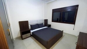Ein Schlafzimmer mit Bett, Nachttischen, einem Fenster und einer Tür.