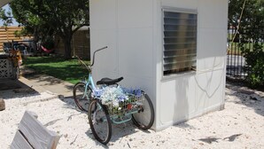 Ein kleiner, weißer Geräte-Schuppen mit Fenster und einem Fahrrad davor.