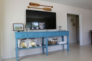 A blue console table with a flat-screen TV above it, a framed picture, and decorative items.