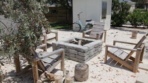Eine Terrasse mit einem Steinkamin, Holzbänken und einem Fahrrad im Hintergrund.