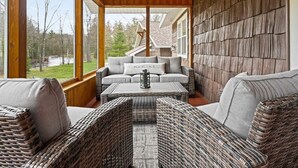 A cozy, enclosed porch with wicker furniture and a view of a house in the background.