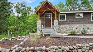 A lodge with a stone facade, wooden porch, and a stone wall surrounding the property.