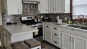 A modern kitchen with white cabinets, a black stove, and a ceiling fan.