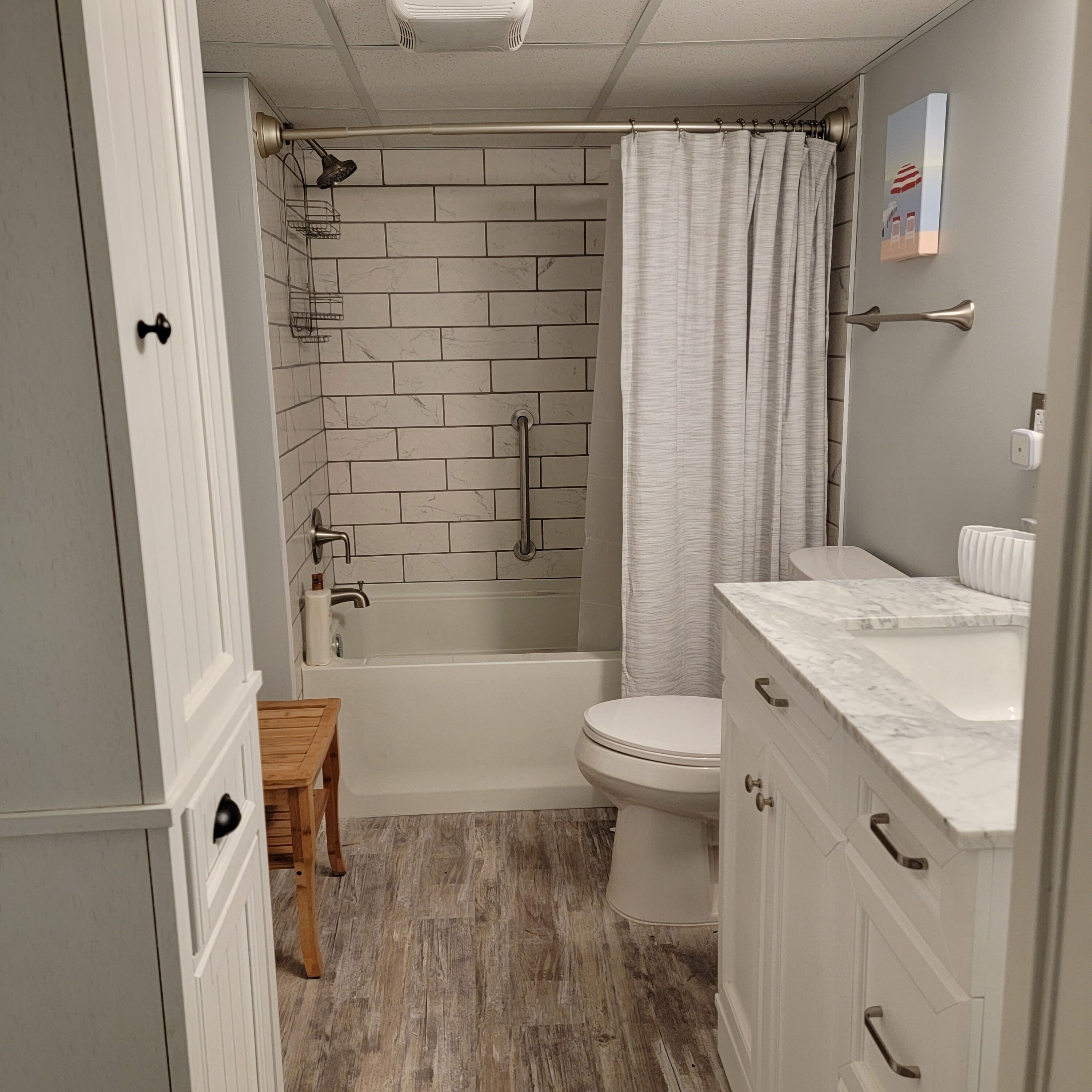 Et badeværelse med bruser, toilet og vaskemøbel.