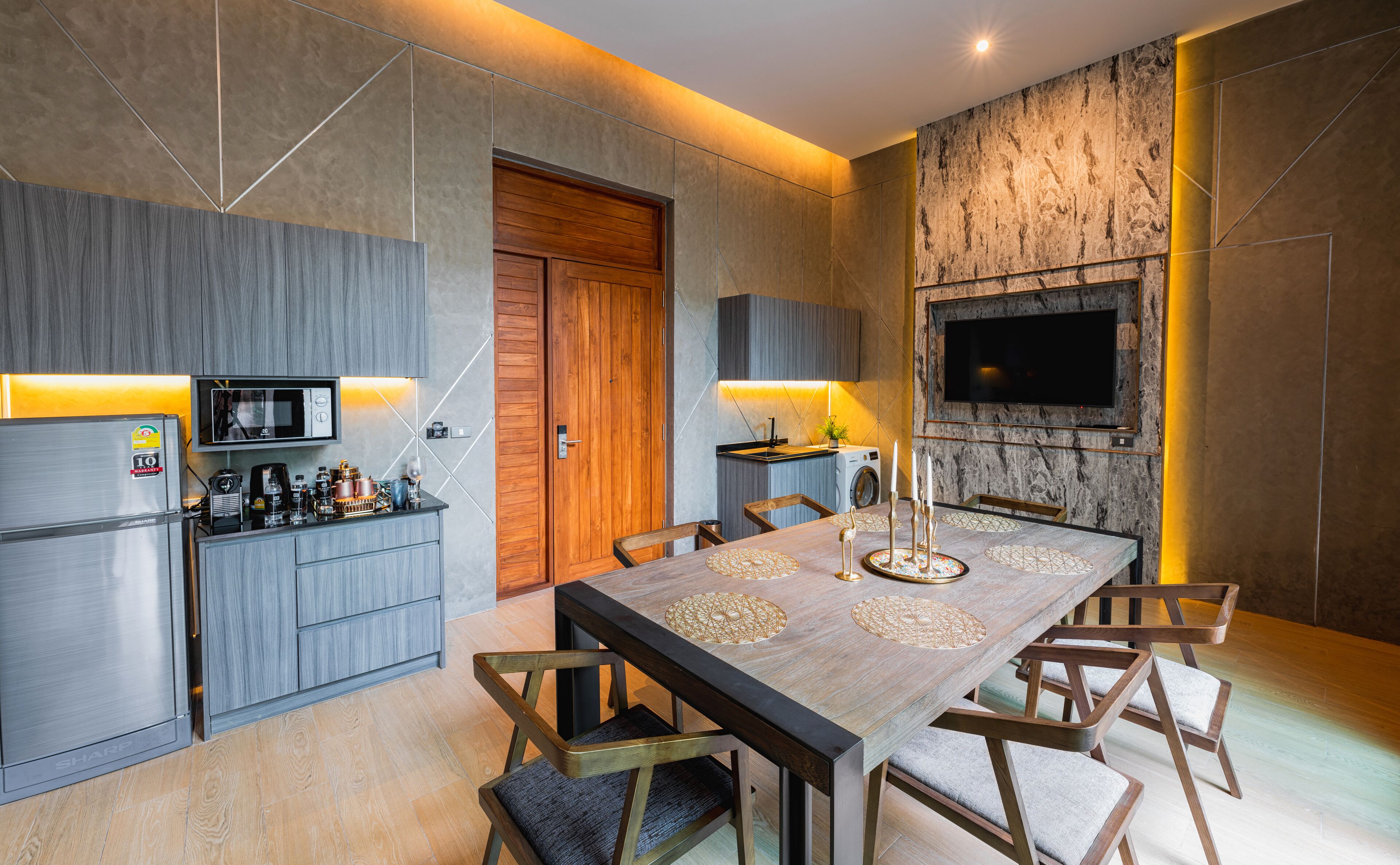 A modern kitchen with a built-in microwave, a wooden door, and a dining area with a marble table and chairs.