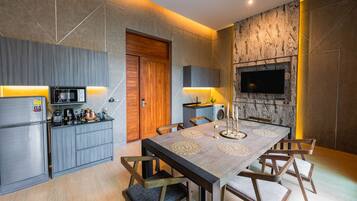 A modern kitchen with a built-in microwave, a wooden door, and a dining area with a marble table and chairs.