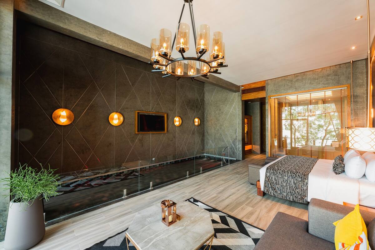 Een moderne hotelkamer met een groot bed, een zithoek met een bijzettafeltje, en een kroonluchter.
