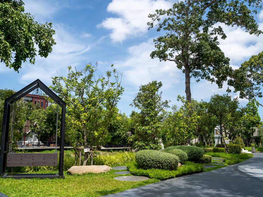 A park with a swing set, well-maintained grass, and trees.