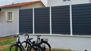 Ein Wohngebiet mit einem weißen Gebäude und einem schwarzen Zaun. Zwei Fahrräder sind an den Zaun gelehnt.