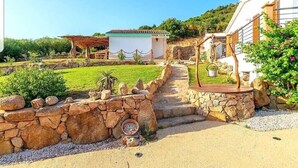 Un sendero de piedra que conduce a una casa rústica con un jardín pequeño y un pabellón.