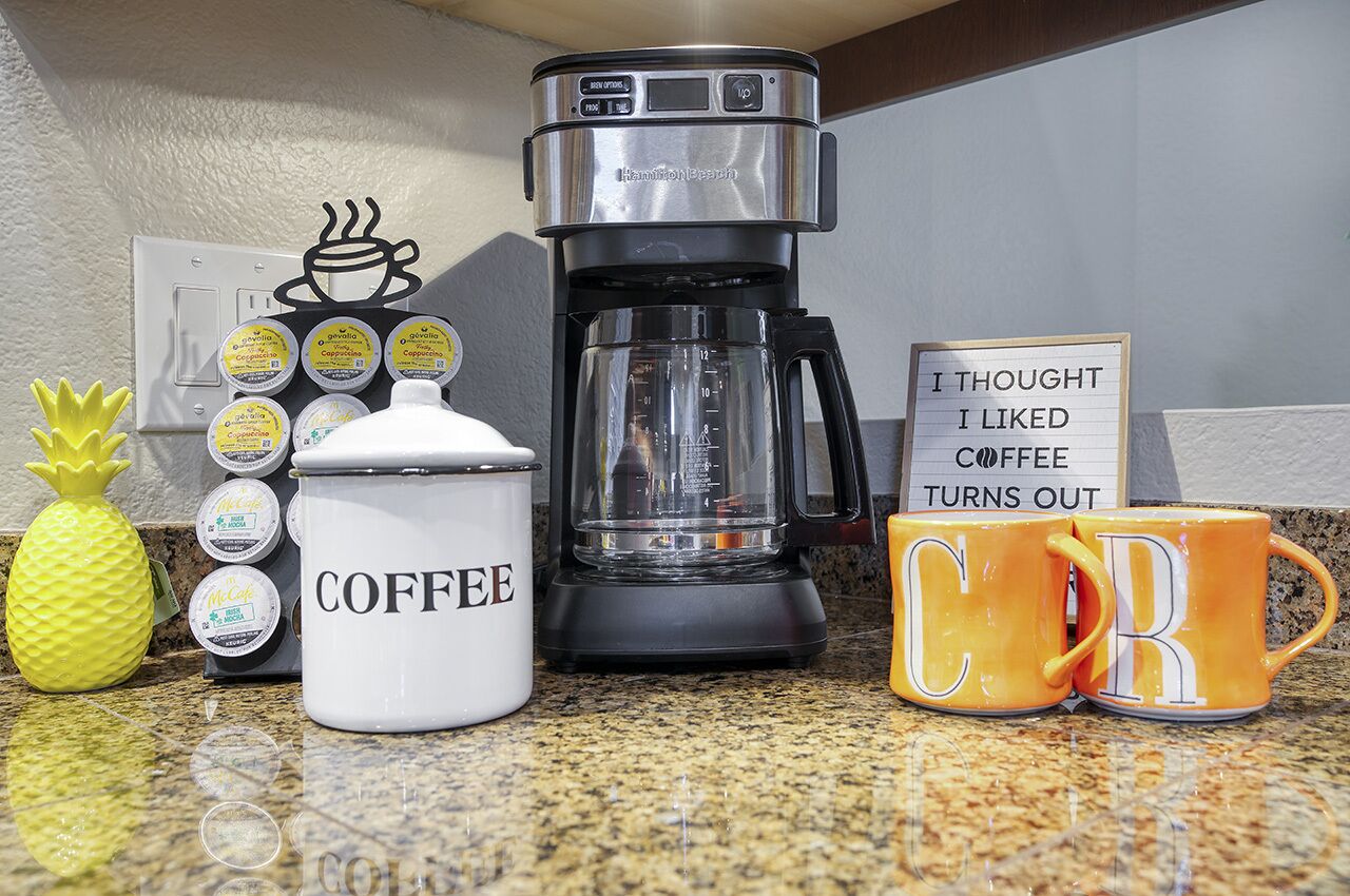 A kitchen counter with a coffee maker, a coffee mug, a container labeled "COFFEE," and a sign that reads "I THOUGHT I LIKED COFFEE TURNS OUT."
