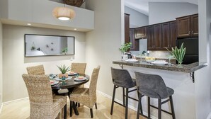 A dining area with a round table, wicker chairs, and a modern pendant light. - Scottsdale - Boho Cactus Condo - Newly Renovated! (Paradise Valley)