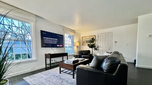 Ein modernes Wohnzimmer mit einer schwarzen Ledersofa, einem Couchtisch und einem flachbildfernseher, der an der Wand montiert ist.