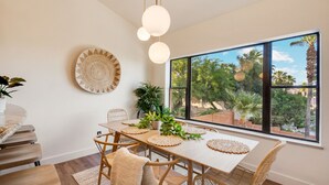 A dining area with a large window, wicker chairs, a white table, and a hanging light fixture. - Amazing Peaceful Resort - Heated Pool, Hot Tub (Fountain Hills)