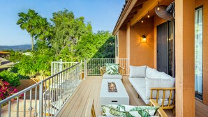 A wooden deck with a white sofa and chairs, a fire feature, and a view of greenery and mountains. - Amazing Peaceful Resort - Heated Pool, Hot Tub (Fountain Hills)