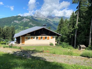 Un chalet de montagne doté d’un toit en pente, d’une façade en bois et de fondations en pierre.