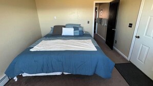 Een slaapkamer met een bed, een deur en een vloer met tapijt.