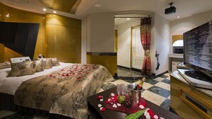 Una habitación de hotel con cama, televisión, minibar y puerta que da a otra habitación.