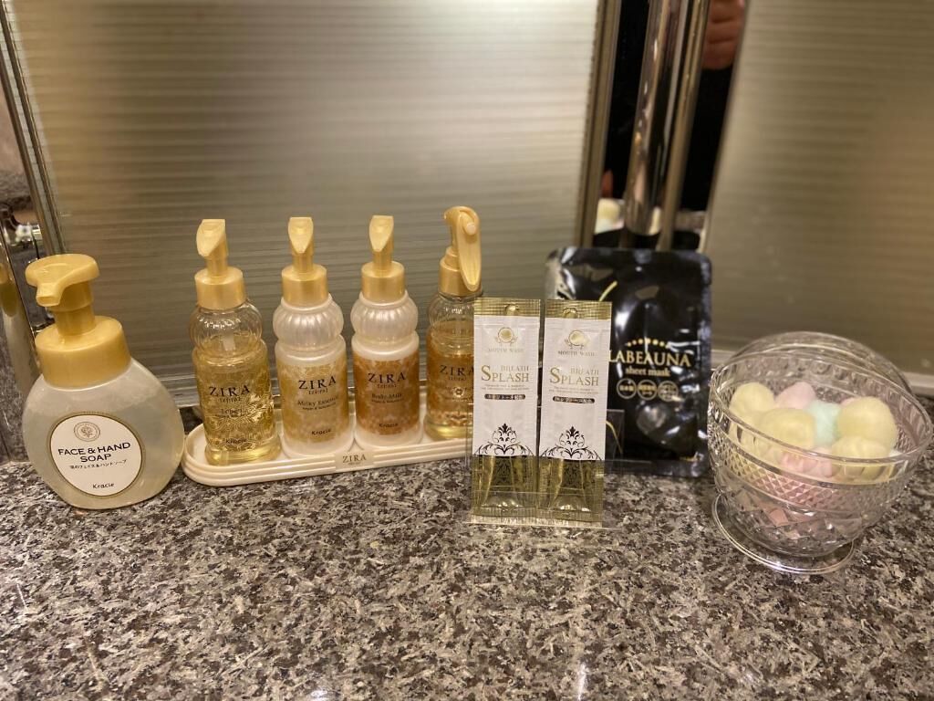 Een aanrecht met diverse persoonlijke verzorgingsproducten, waaronder flessen gezichts- en handzeep, douchegel en parfum.