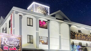 Un hotel con un cartel que dice 'Hotel Restay' y un letrero iluminado grande en el techo.