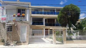 A two-story building with a gated entrance, a balcony on the upper floor, and a staircase leading to the entrance. - Fully Equipped New 2br Apt-dt2mins To The Beach (Sosúa)