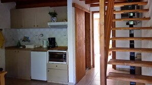 A compact kitchen with wooden beams, a built-in oven, and a small refrigerator. - Exclusive Cottages in a Quiet Oliverove Near the sea (Kantanos-Selino)