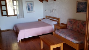 A cozy room with a wooden bed, a bench, a sofa, and a window with curtains. - Exclusive Cottages in a Quiet Oliverove Near the sea (Kantanos-Selino)