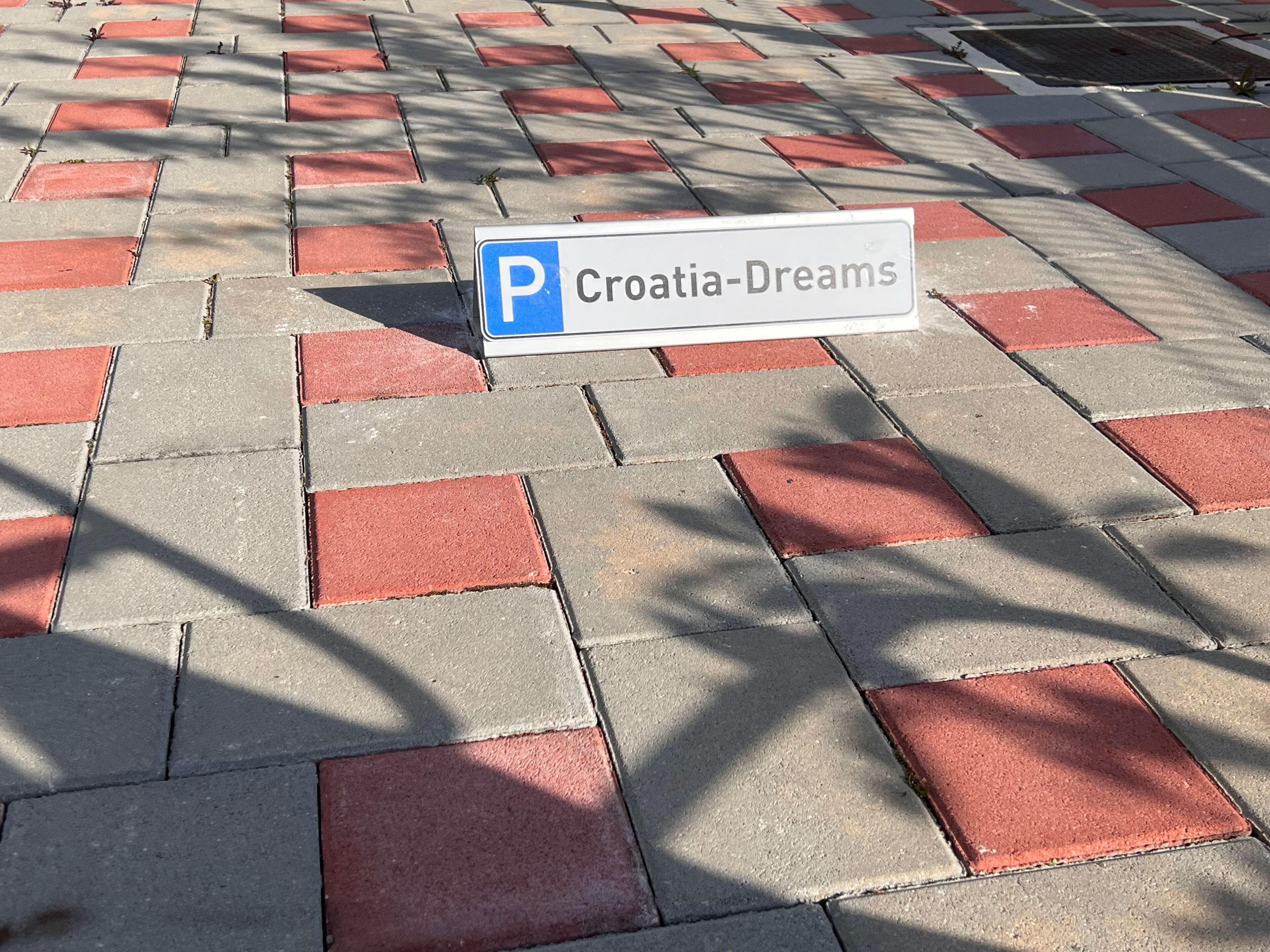 A parking sign labeled 'Croatia-Dreams' on a patterned pavement.