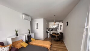 Un espacio habitable compacto con kitchenette, comedor y dos camas.