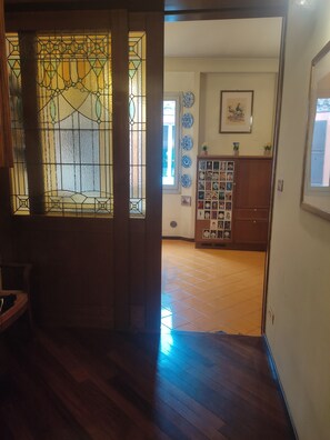 Une pièce dotée d’un plancher en bois, d’une porte donnant sur une autre pièce et d’un mur orné de tableaux encadrés et d’assiettes bleues.