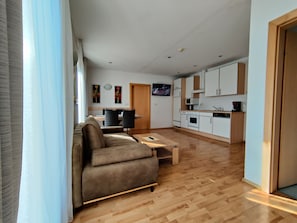 A modern apartment with a living room, dining area, and kitchen.