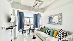 Una sala moderna con sofá, televisor, mesa de comedor y sillas.