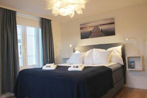 A neatly made bed with white linens, a headboard, and a bedside table with a lamp. - Casa Schilling 2,5 Rooms in St Gallen, Modern, Quiet and Close to the Center (St. Gallen)