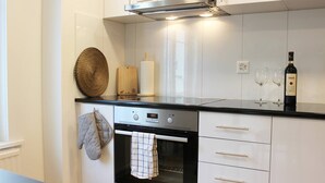 A modern kitchen with white cabinetry, a stainless steel oven, and a digital clock. - Casa Schilling 2,5 Rooms in St Gallen, Modern, Quiet and Close to the Center (St. Gallen)