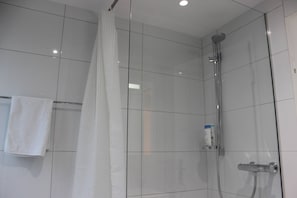 A modern bathroom with white tiled walls, a glass shower enclosure, a towel rack, and a handheld showerhead. - Casa Schilling 2,5 Rooms in St Gallen, Modern, Quiet and Close to the Center (St. Gallen)