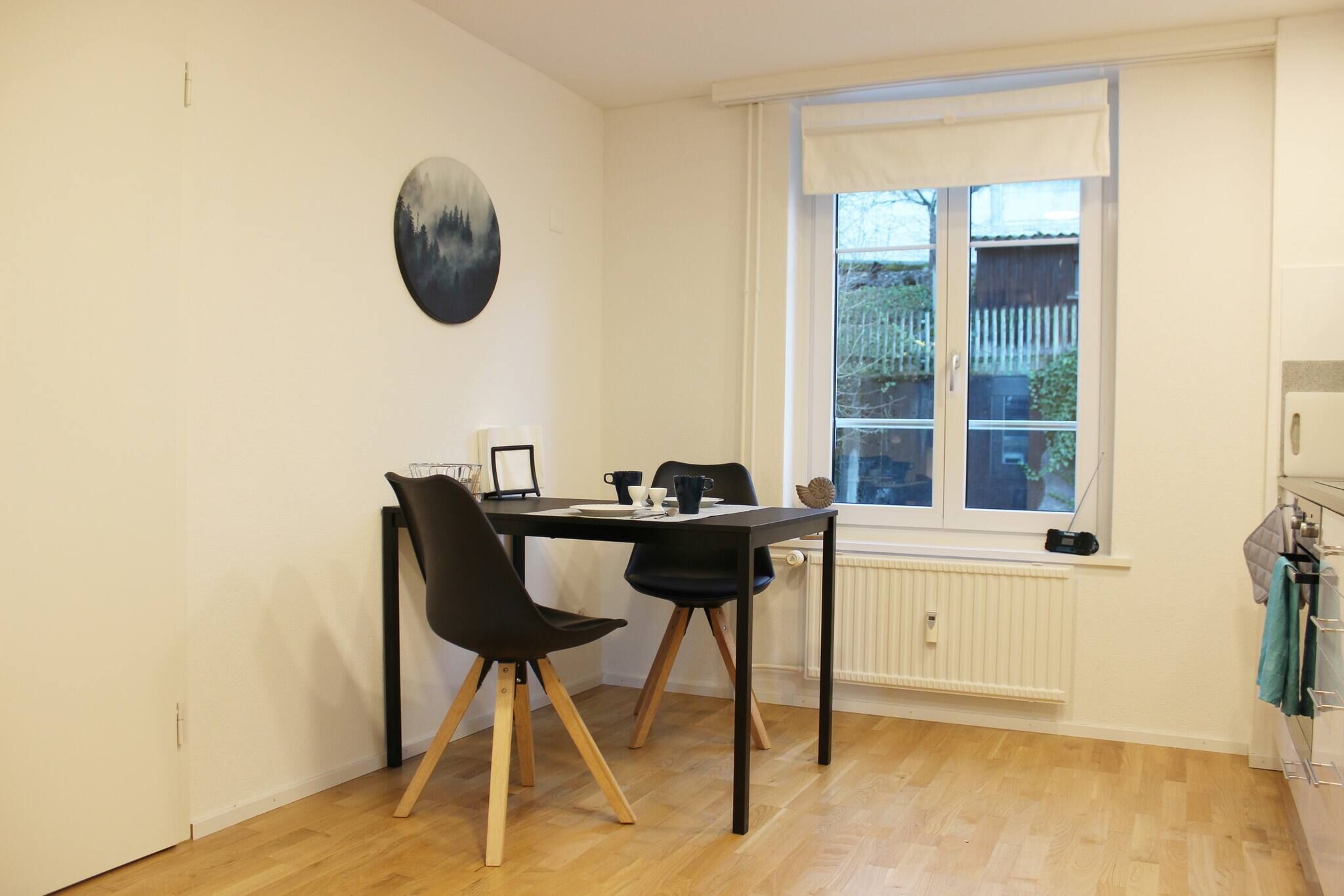 Un comedor con mesa y sillas, una ventana con vistas, y un radiador.