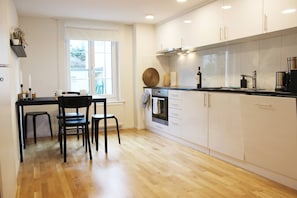 A modern kitchen with white cabinets, a black countertop, and a wooden floor. - Casa Schilling 2,5 Rooms in St Gallen, Modern, Quiet and Close to the Center (St. Gallen)