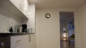 A modern kitchen with white cabinets, a coffee maker, and a clock on the wall. - Casa Schilling 2,5 Rooms in St Gallen, Modern, Quiet and Close to the Center (St. Gallen)