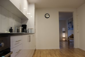A modern kitchen with white cabinets, a coffee maker, and a clock on the wall. - Casa Schilling 2,5 Rooms in St Gallen, Modern, Quiet and Close to the Center (St. Gallen)