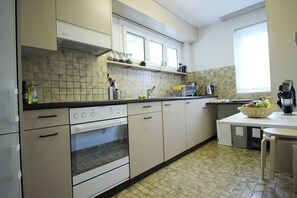 A kitchen with white cabinets, a stove, an oven, a sink, and a window.