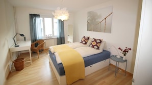 A bedroom with a bed, desk, chair, and a small table with a vase. - Casa Schilling- 2,5 Rooms With Balcony Near Hospital, University (St. Gallen)