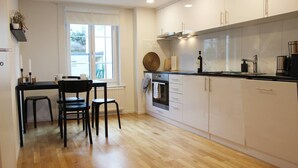 Une cuisine moderne avec des meubles blancs, un plancher en bois et un coin repas doté de chaises noires.