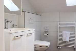 A modern bathroom with a white sink, toilet, and towel rack.