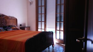 A bedroom with a wooden bed, a nightstand, and a window with blinds. - Room With a sea View (Cogorno)