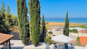 Zona de piscina con vista al mar, rodeada de altos árboles y cielo despejado.